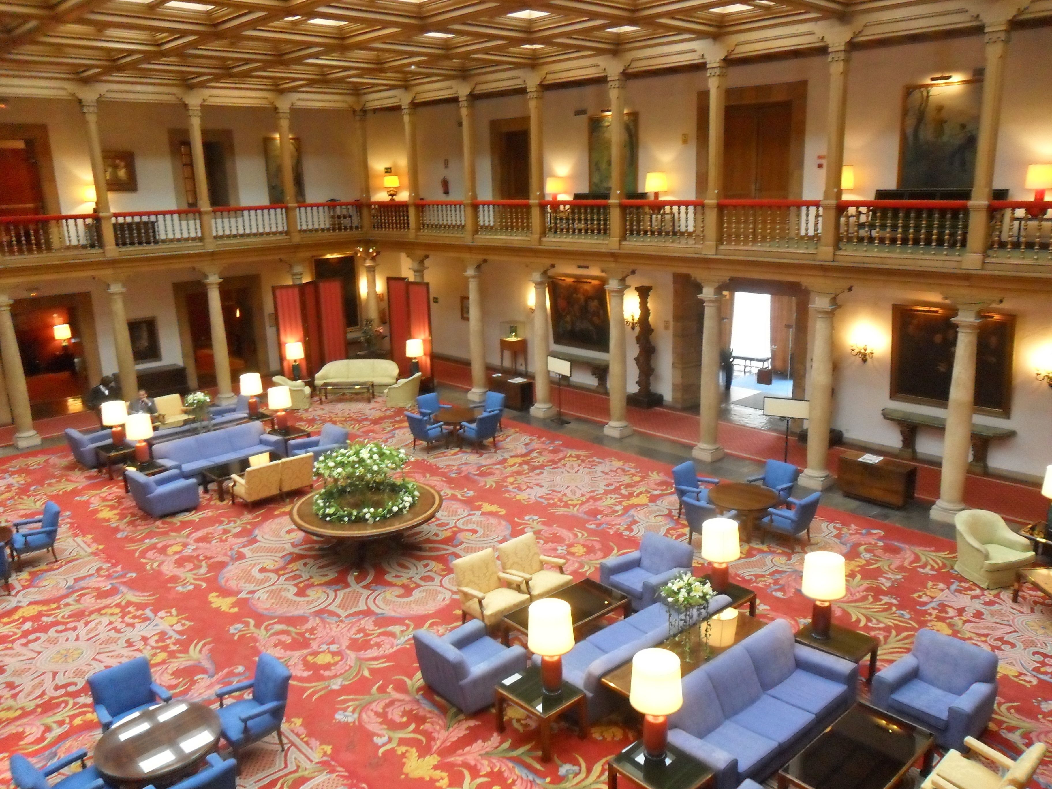 A spacious lobby with a central floral arrangement, multiple seating areas, and a high ceiling with ornate columns.