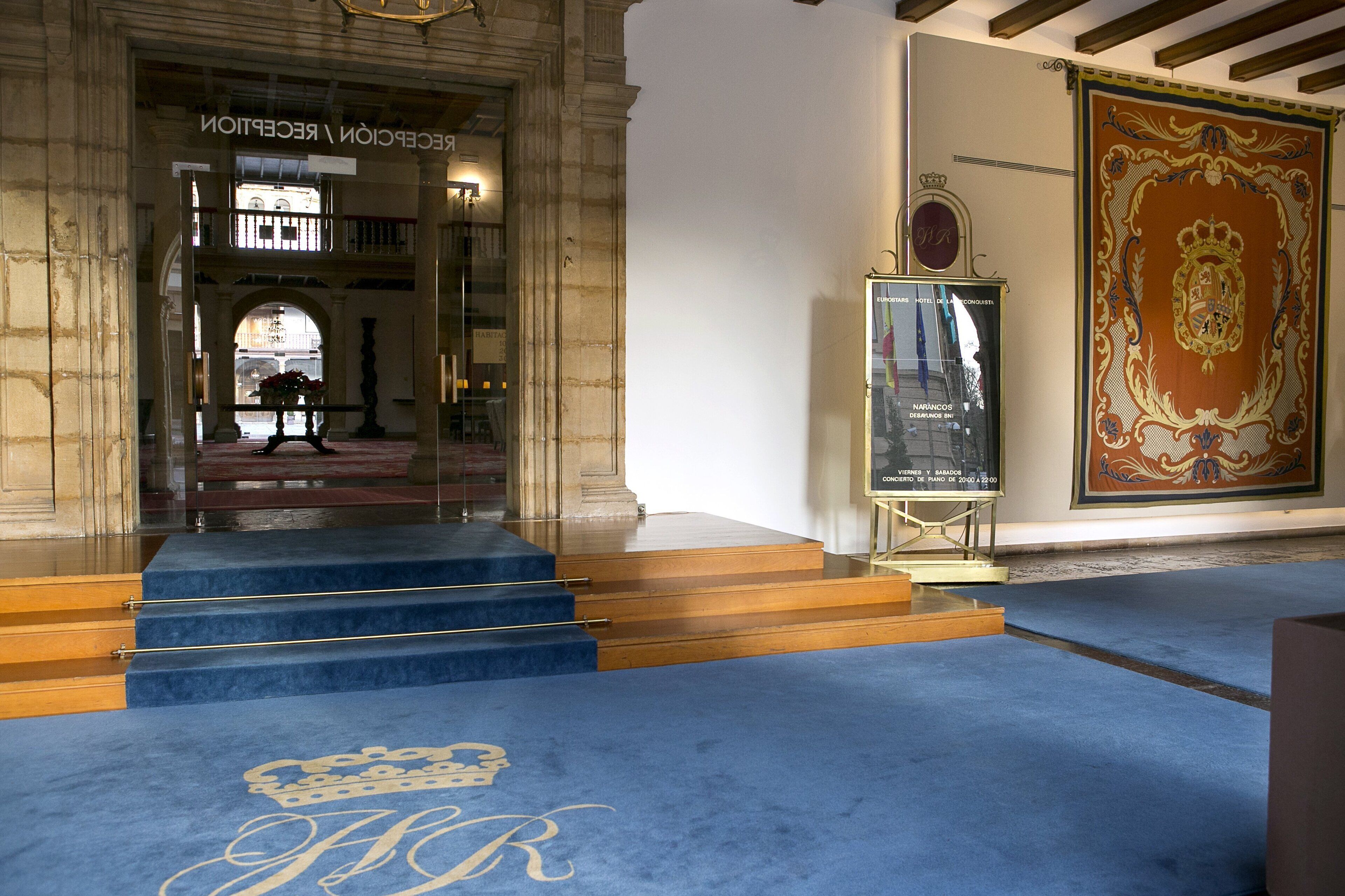 Una entrada imponent amb una catifa blava que presenta un emblema de corona, que condueix a un balcó amb vistes.