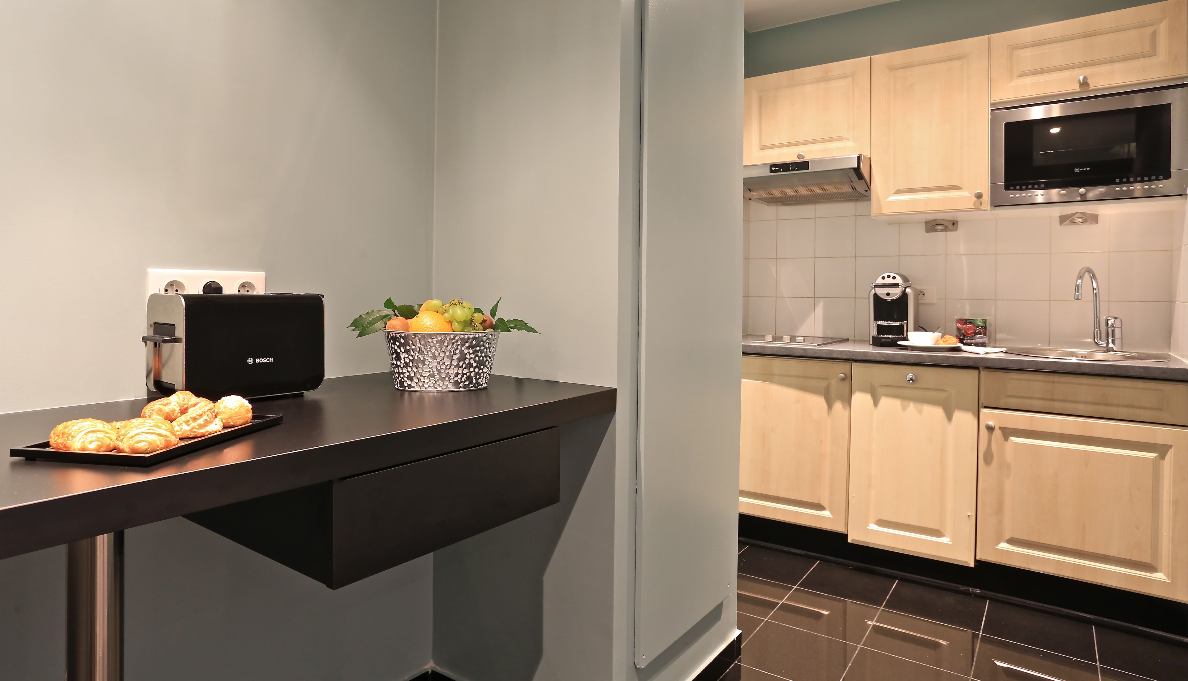 Una cocina moderna con un tostador Bosch, una cesta de fruta y una bandeja de cruasanes.
