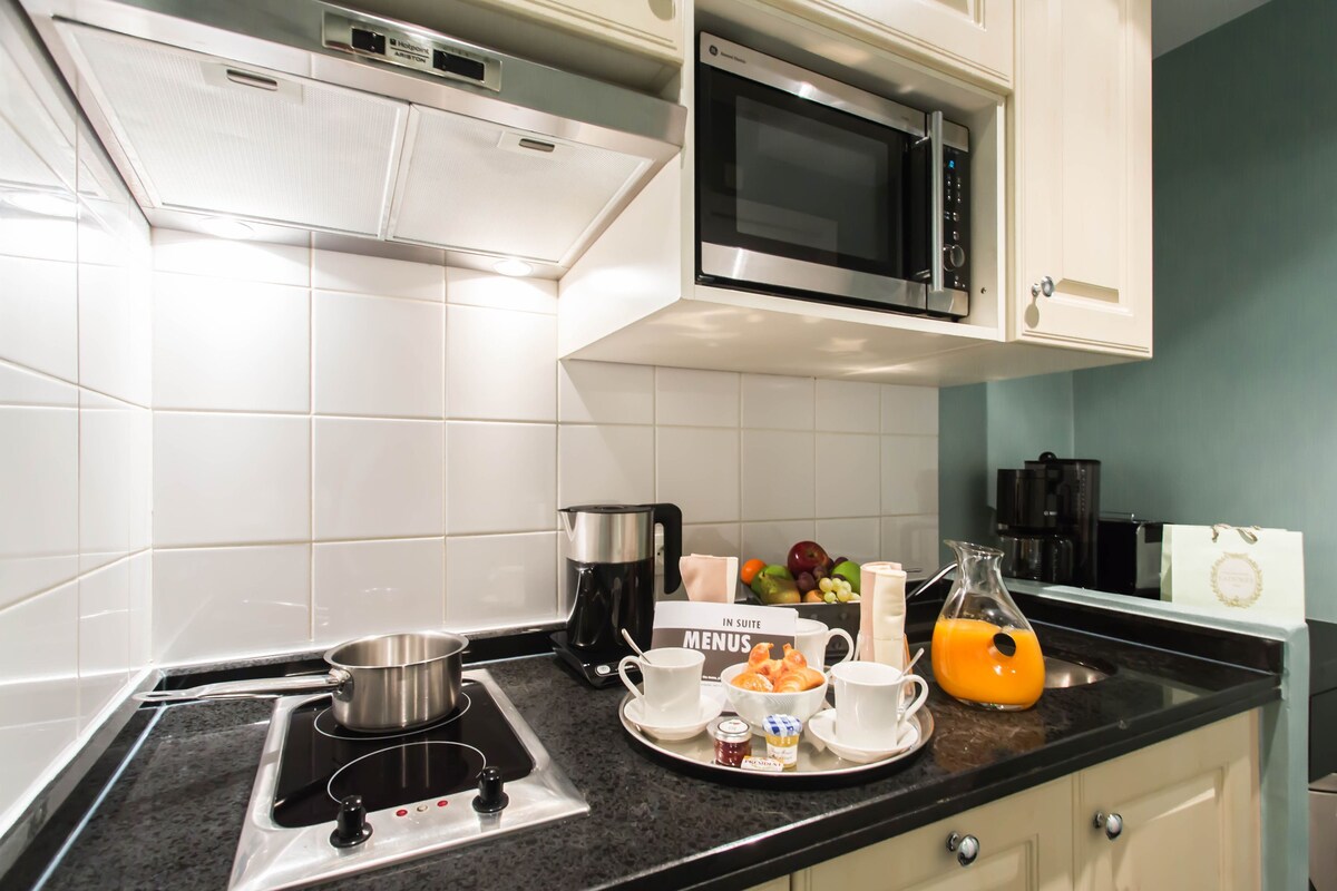 Une cuisine équipée d’un four à micro-ondes, d’une cuisinière, d’une machine à café et d’un plateau avec des tasses et une carafe de jus d’orange.