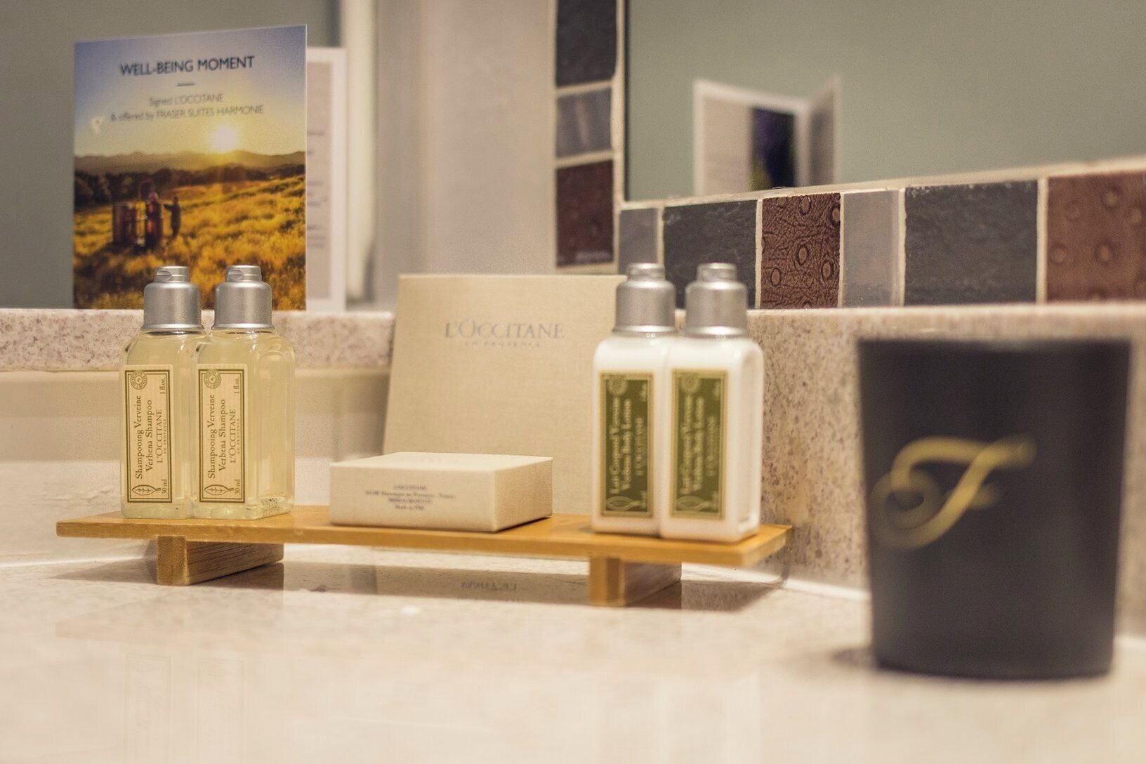 A bathroom vanity with toiletries, a sign, and a mirror.