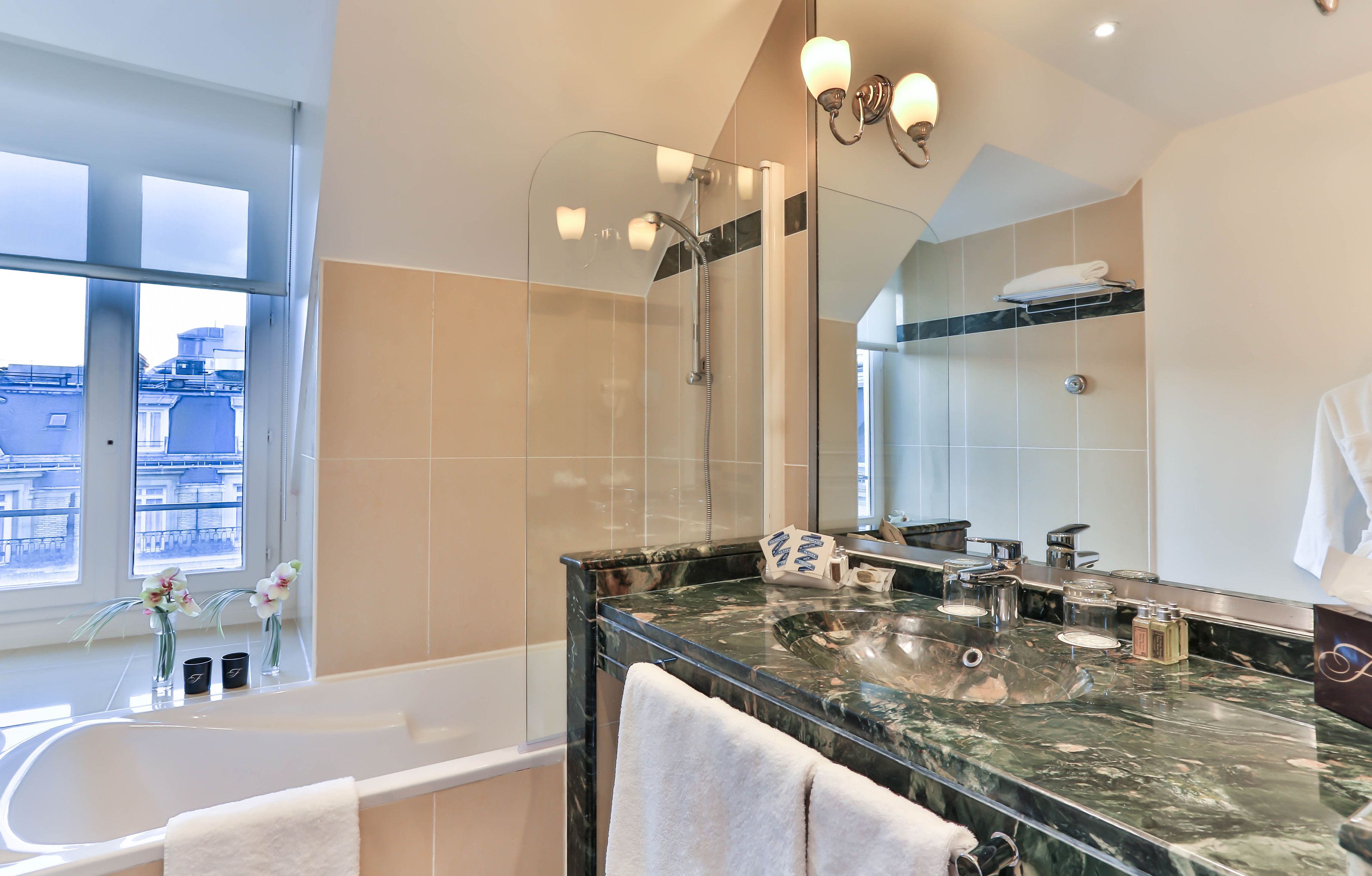 Un baño moderno con un espejo grande, una bañera y un tocador con encimera de mármol.