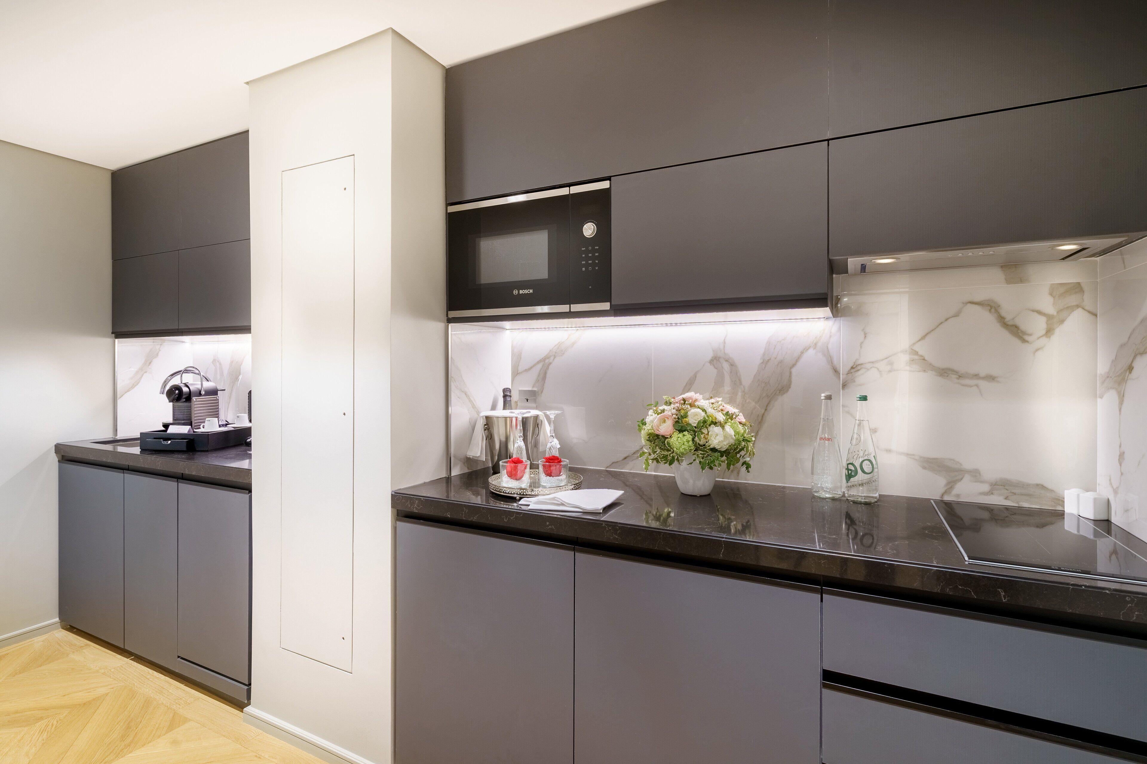 Una cocina moderna con armarios oscuros, un microondas Bosch y un salpicadero de mármol.