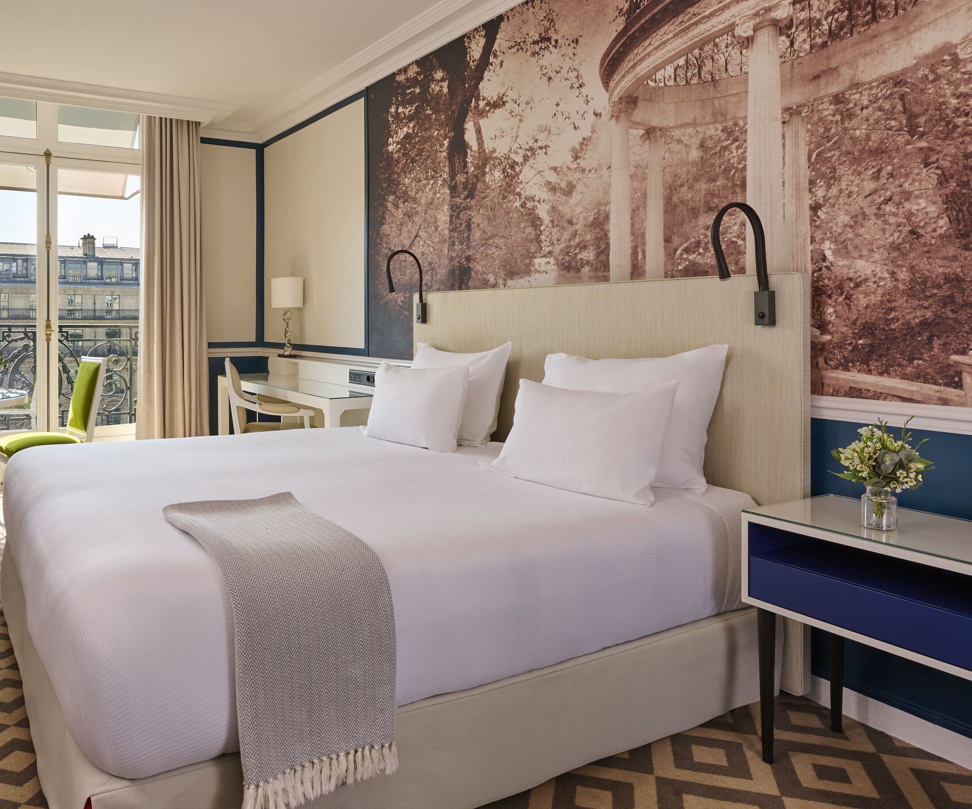 Habitación de hotel con una cama grande, un escritorio y vistas a la ciudad.