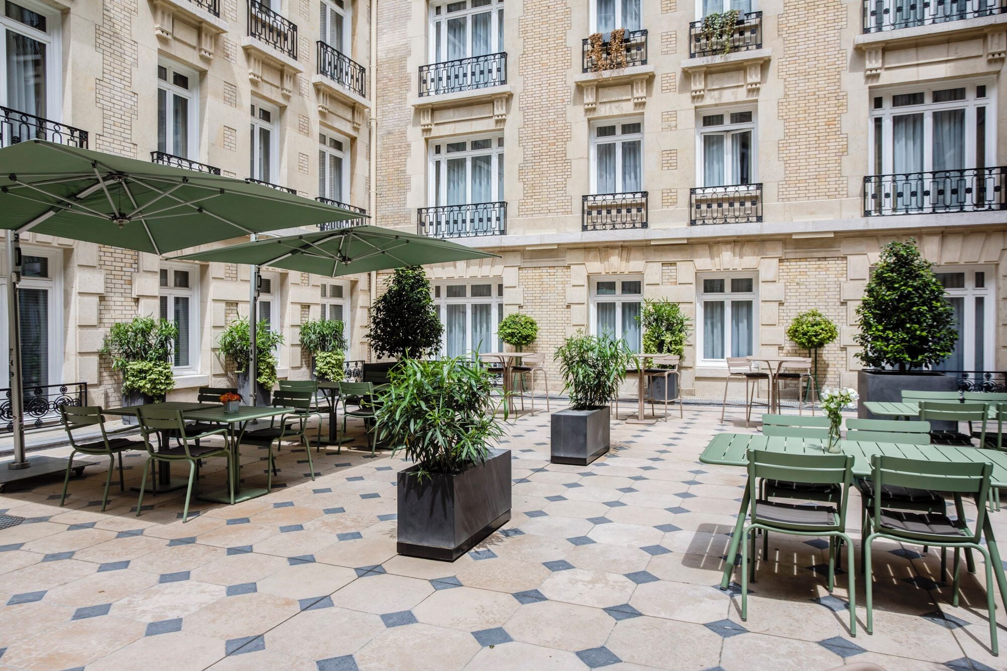 A courtyard with outdoor seating, potted plants, and a tiled floor.