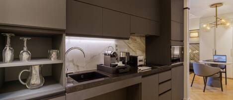 A modern kitchen with dark cabinetry, a marble backsplash, and a built-in coffee maker.
