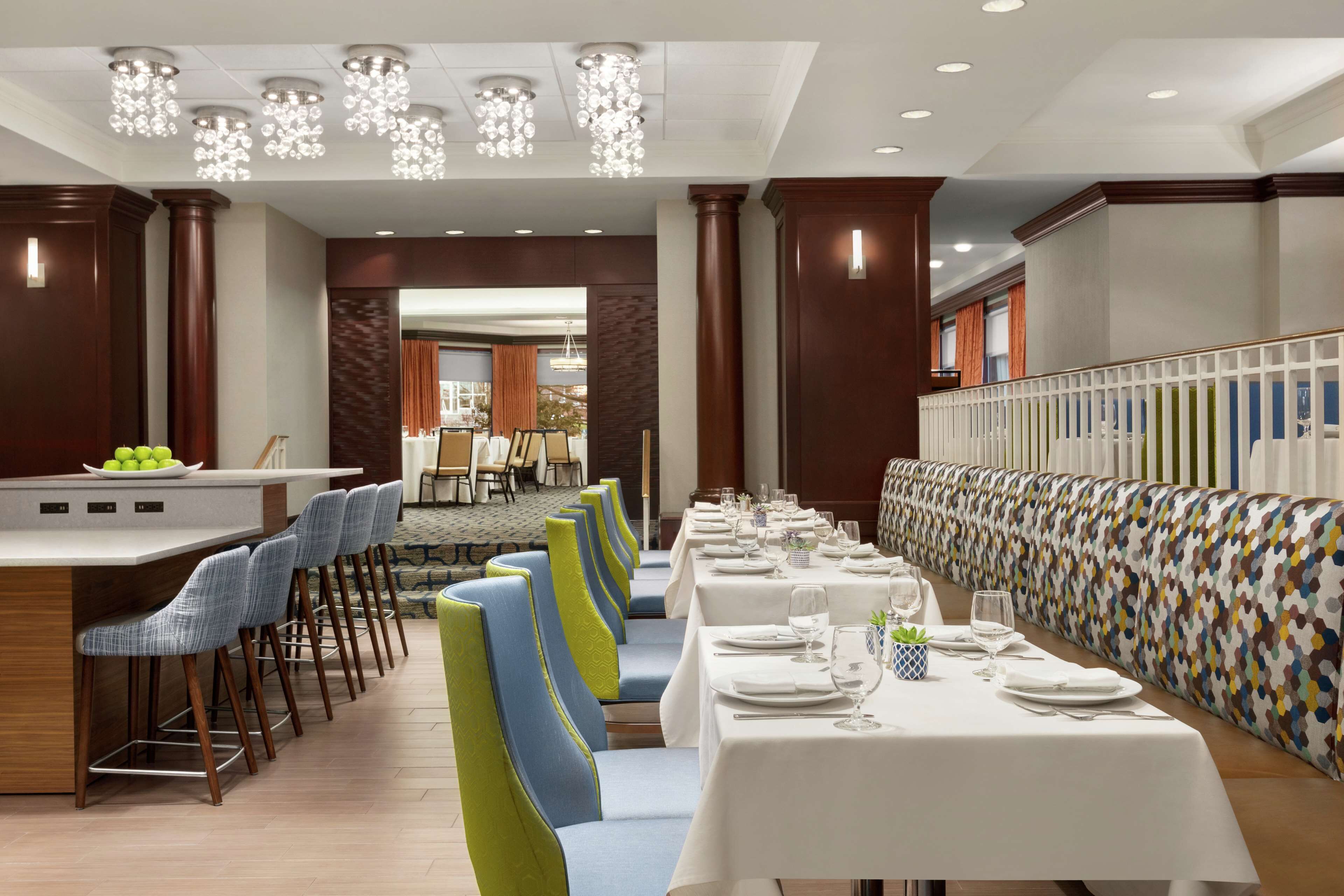 A restaurant with a long counter, multiple tables, and chairs.