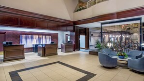 A spacious lobby with a reception desk, seating area, and a staircase leading to an upper level. - Embassy Suites by Hilton Boston Waltham (Waltham)