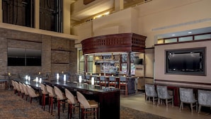 A conference room with a long table, chairs, a bar area, and a television screen. - Embassy Suites by Hilton Boston Waltham (Waltham)