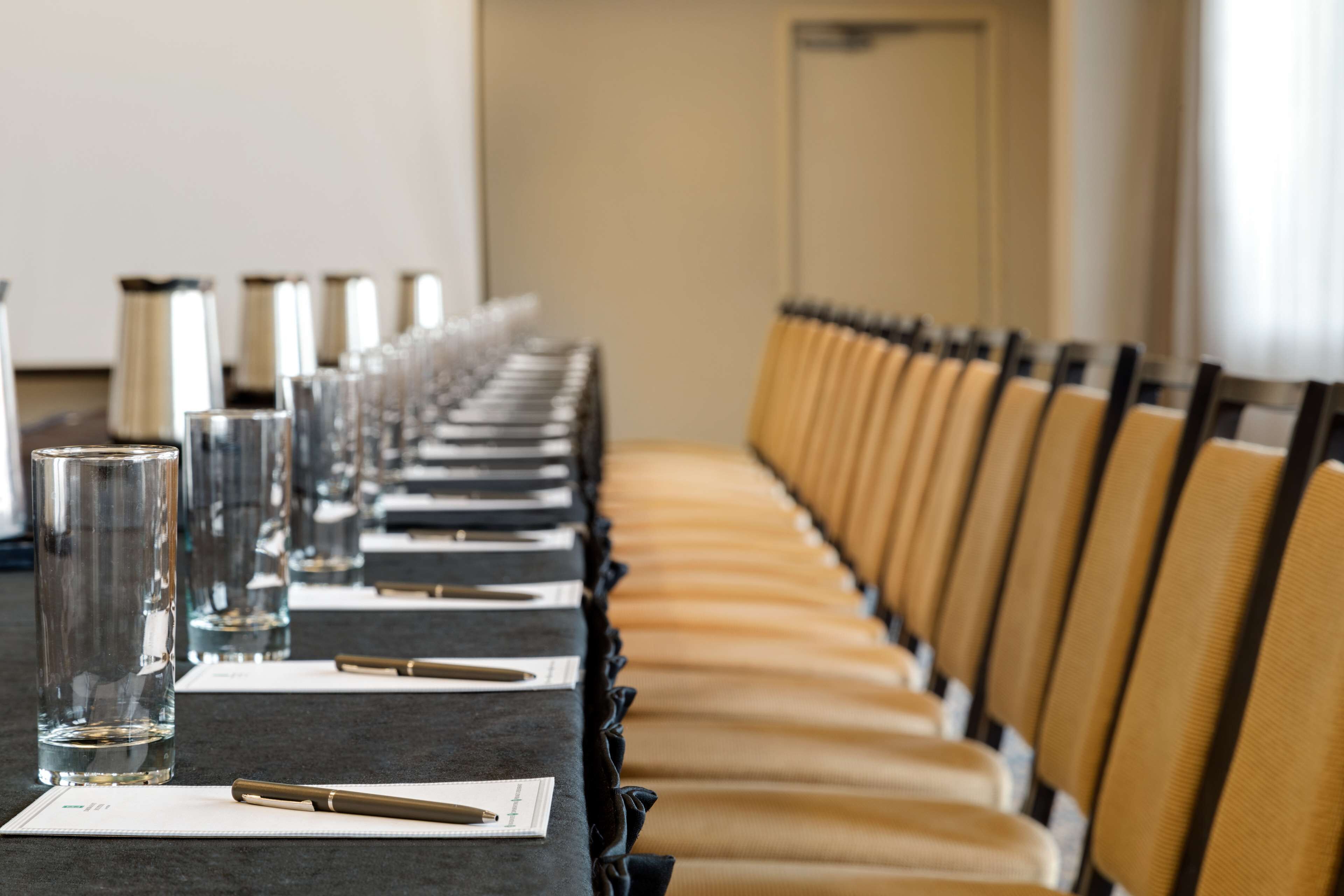 Uma sala de conferência com uma mesa comprida, cadeiras e copos d'água.