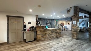 A spacious lobby with a reception desk, a stone accent wall, and a wooden floor. - Alpine Inn & Suites (Gunnison)
