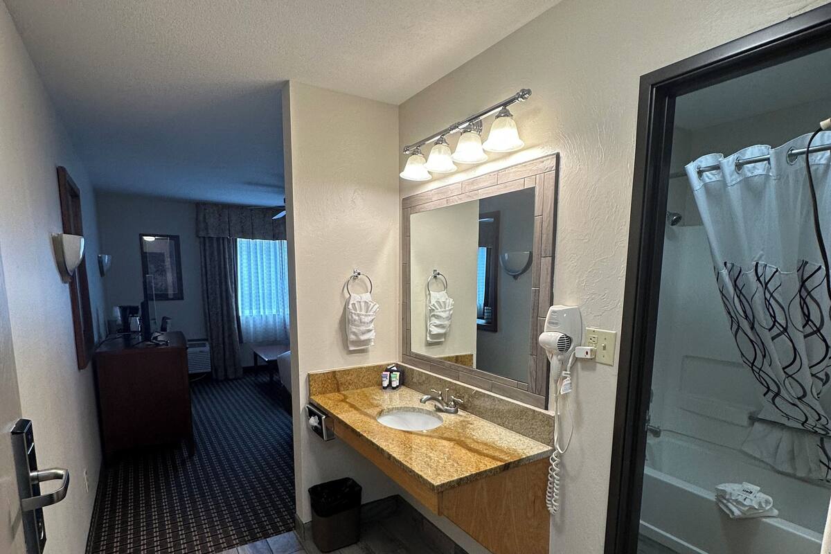 A bathroom with a sink, mirror, and shower curtain.