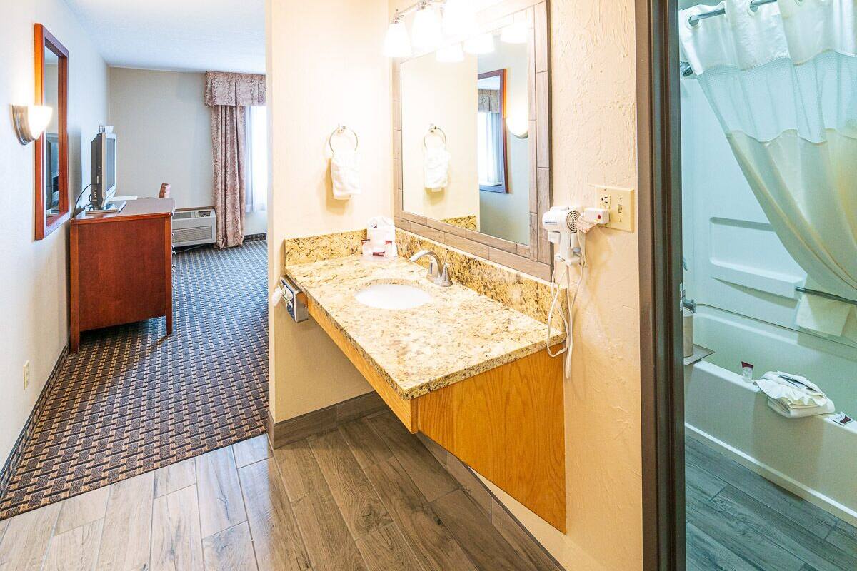 A hotel bathroom with a sink, mirror, and shower.