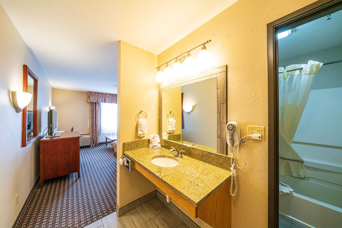 A hotel bathroom with a sink, mirror, and shower.