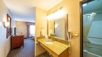 A hotel bathroom with a sink, mirror, and shower.