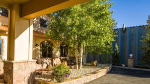 A covered outdoor area with a stone wall, a tree, and a statue of a deer. - Alpine Inn & Suites (Gunnison)