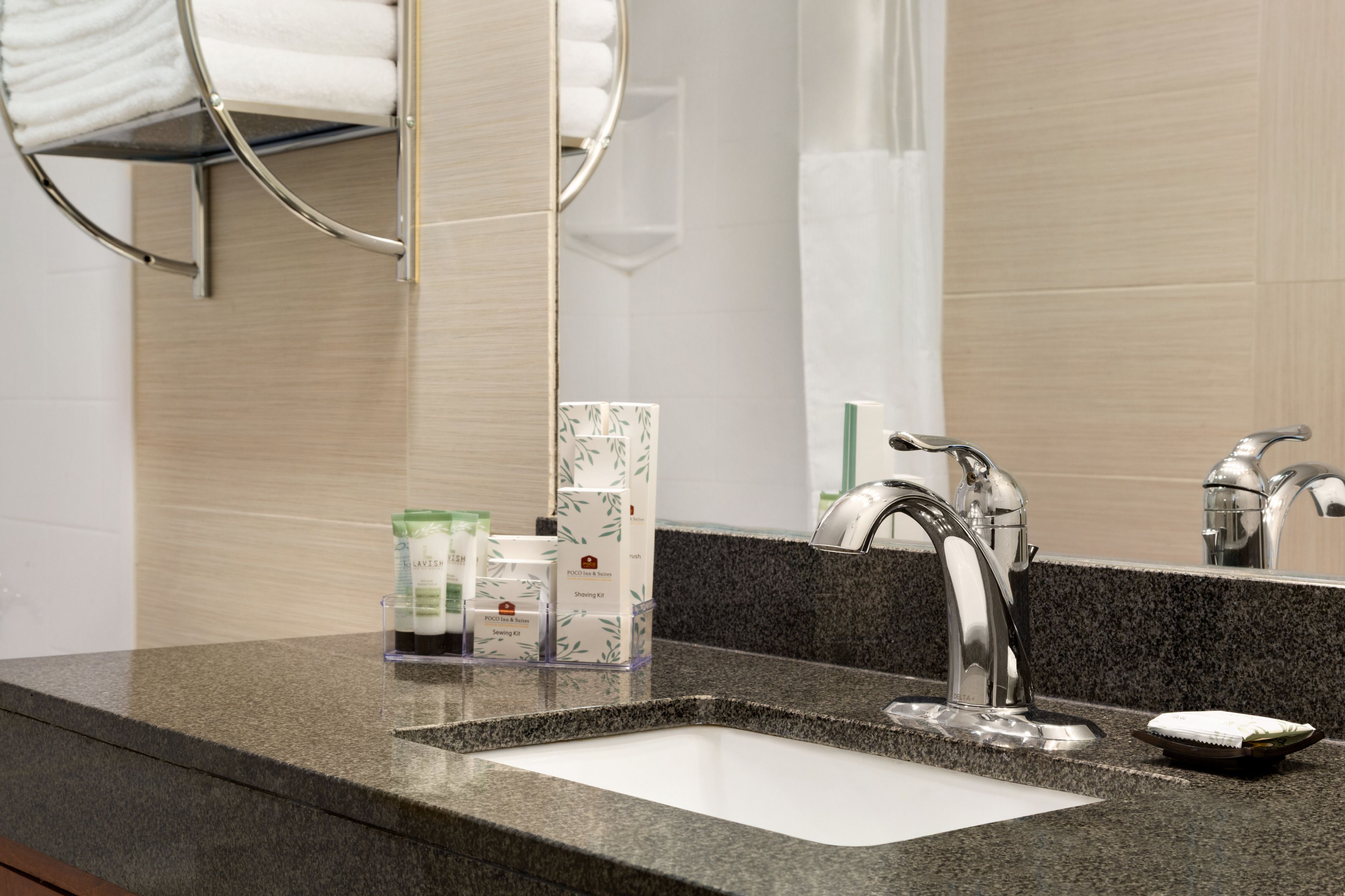 Un baño moderno con encimera de granito, lavamanos doble y perchero.