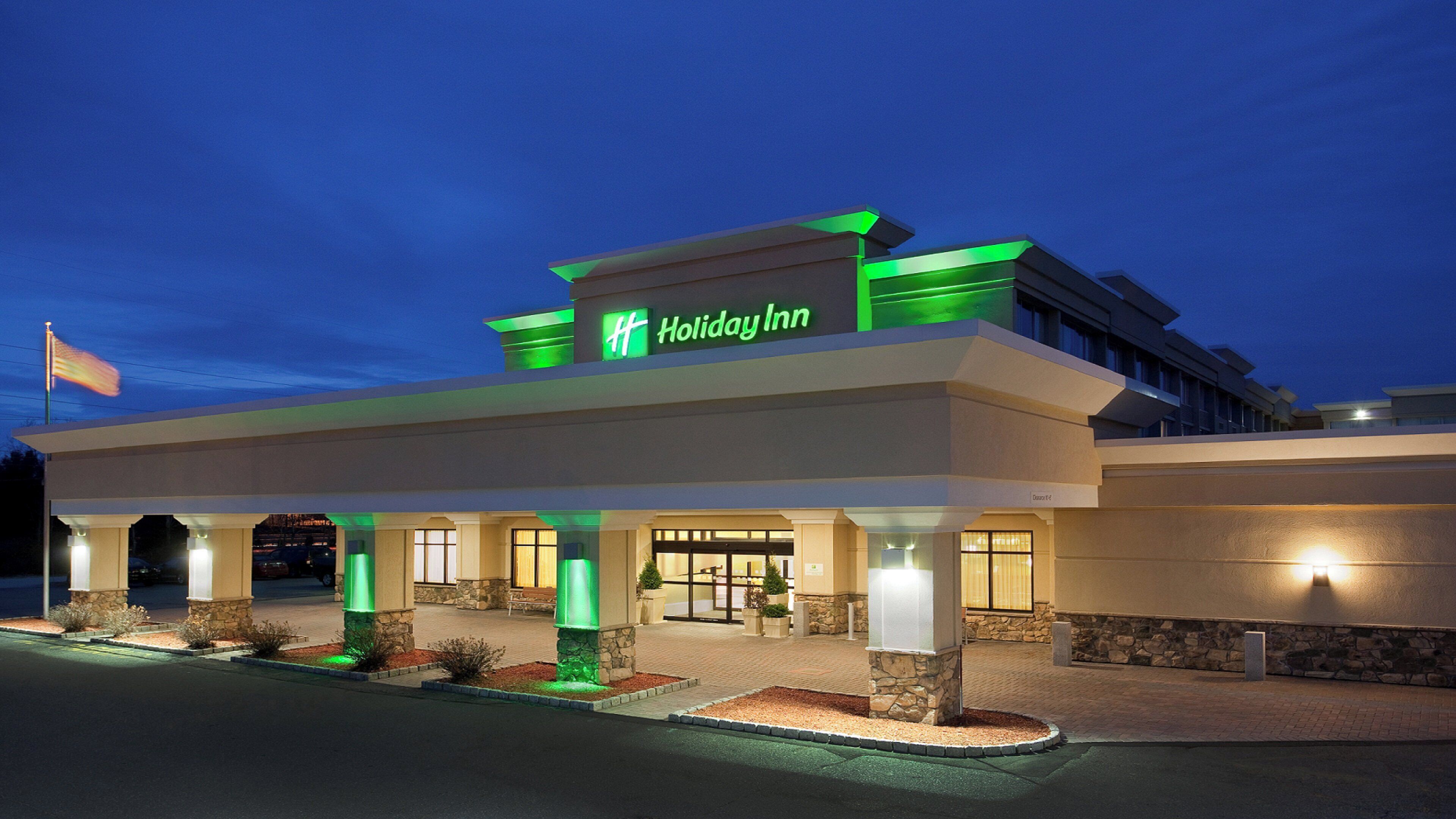 A Holiday Inn hotel with a modern facade, a prominent sign, and a well-lit entrance.