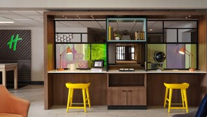 A modern kitchen with two yellow stools, a wooden counter, and a view of the dining area.