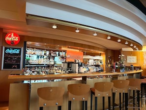 A bar area with a Coca-Cola sign, a menu board, and a variety of bottles and glasses. - Hotel Meerane (Meerane)