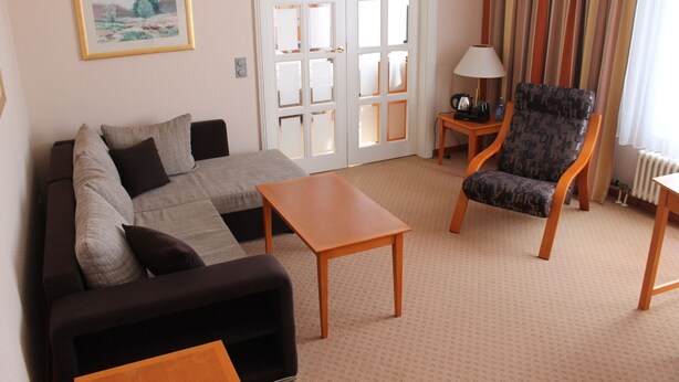 A living room with a sofa, a chair, a coffee table, a lamp, and a door with glass panels.