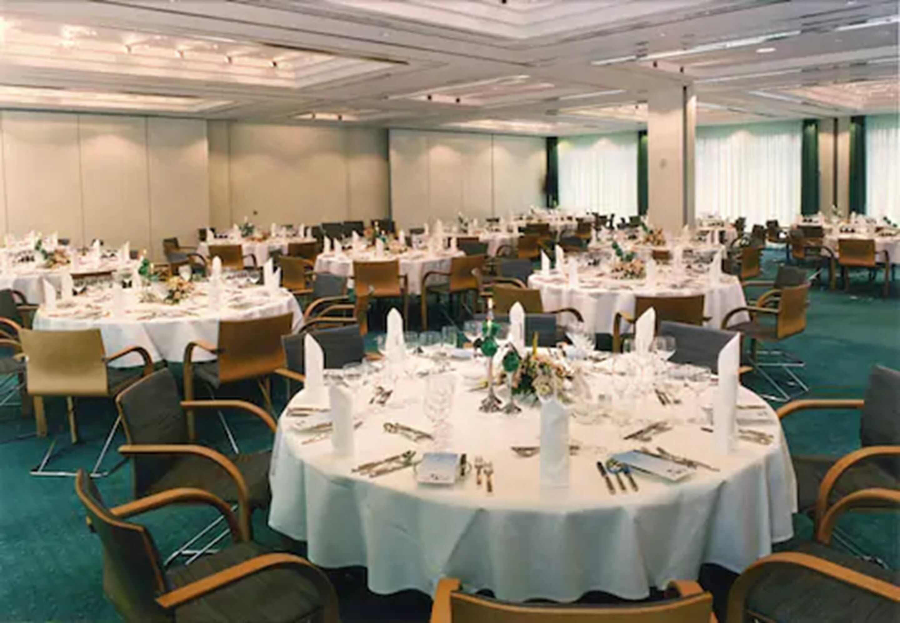 Un salón de banquetes con mesas redondas dispuestas para cenar, organizadas en filas.