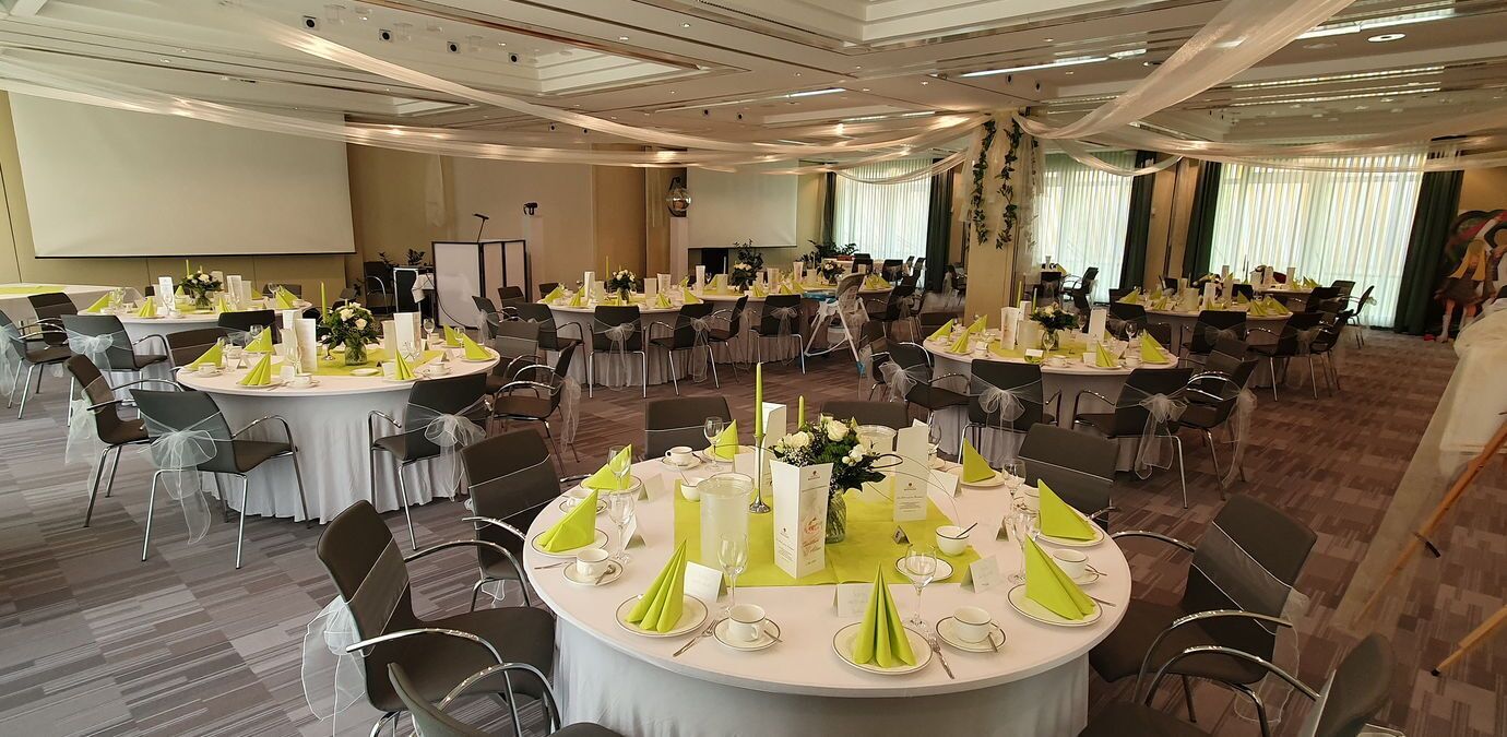 A conference room with round tables, chairs, and a projector screen.