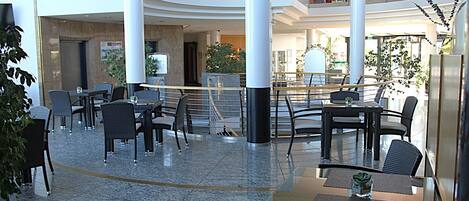 A spacious indoor area with multiple seating arrangements, including tables and chairs, and a central column structure.