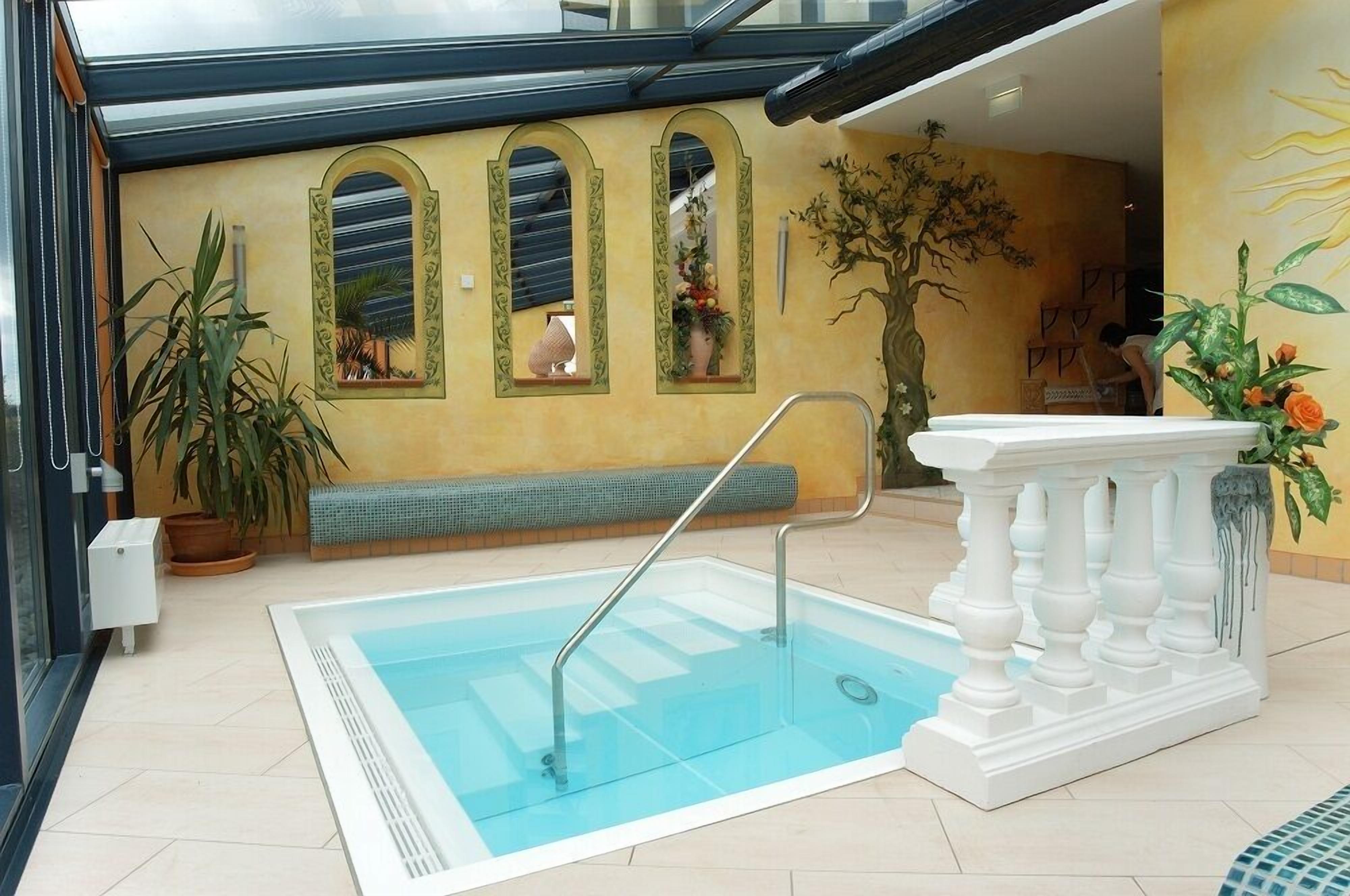 Una piscina con barandilla blanca, una banca y una planta en maceta cerca.