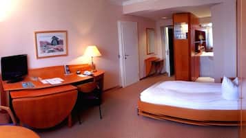 Une chambre d’hôtel équipée d’un lit, d’un bureau, d’une chaise, d’une télévision et d’un miroir.