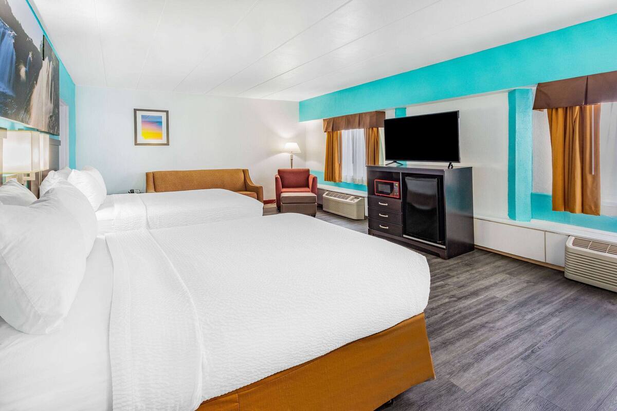 A hotel room with a large bed, a TV, a desk, and a chair.