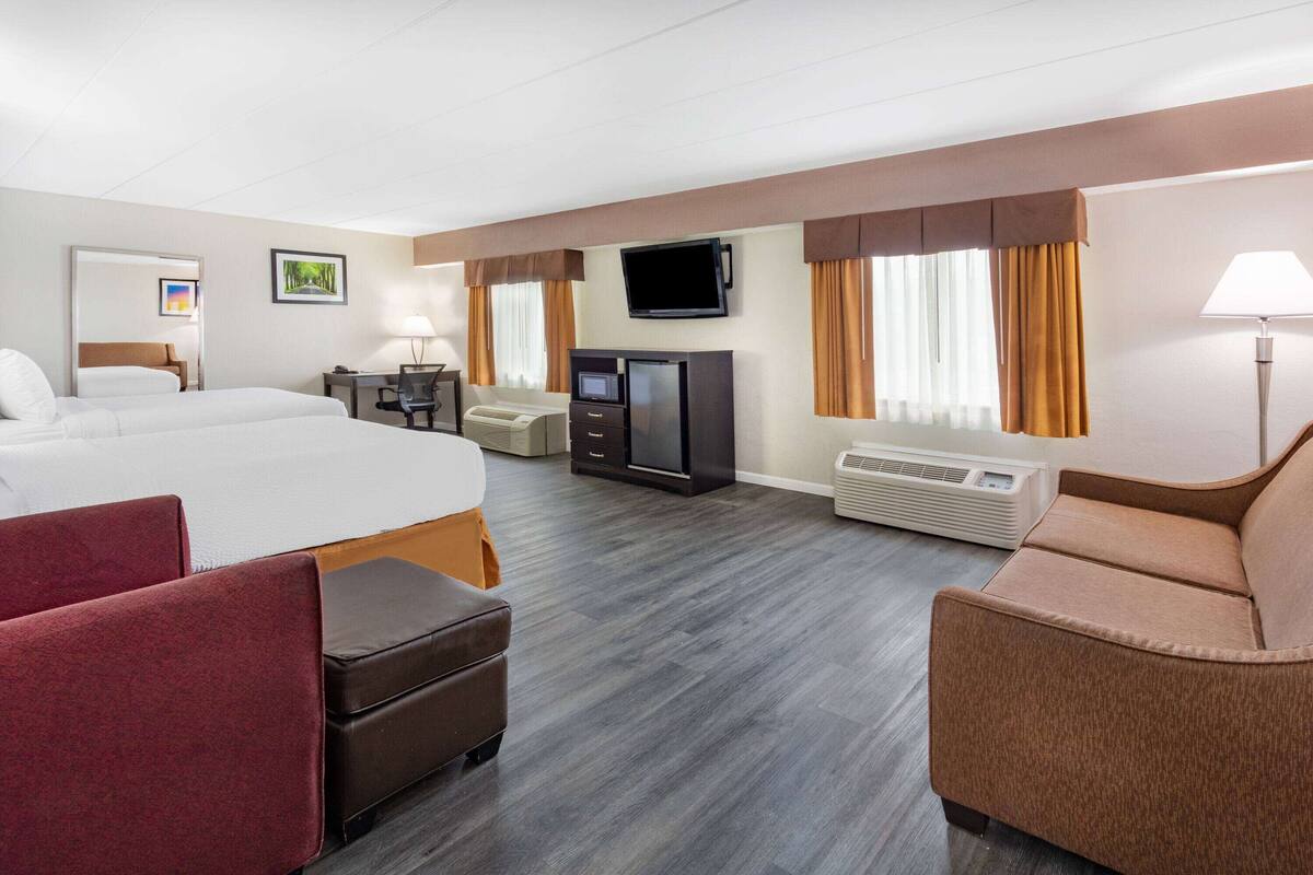 A hotel room with a large bed, a desk with a computer, a television, and a seating area with a couch and chairs.