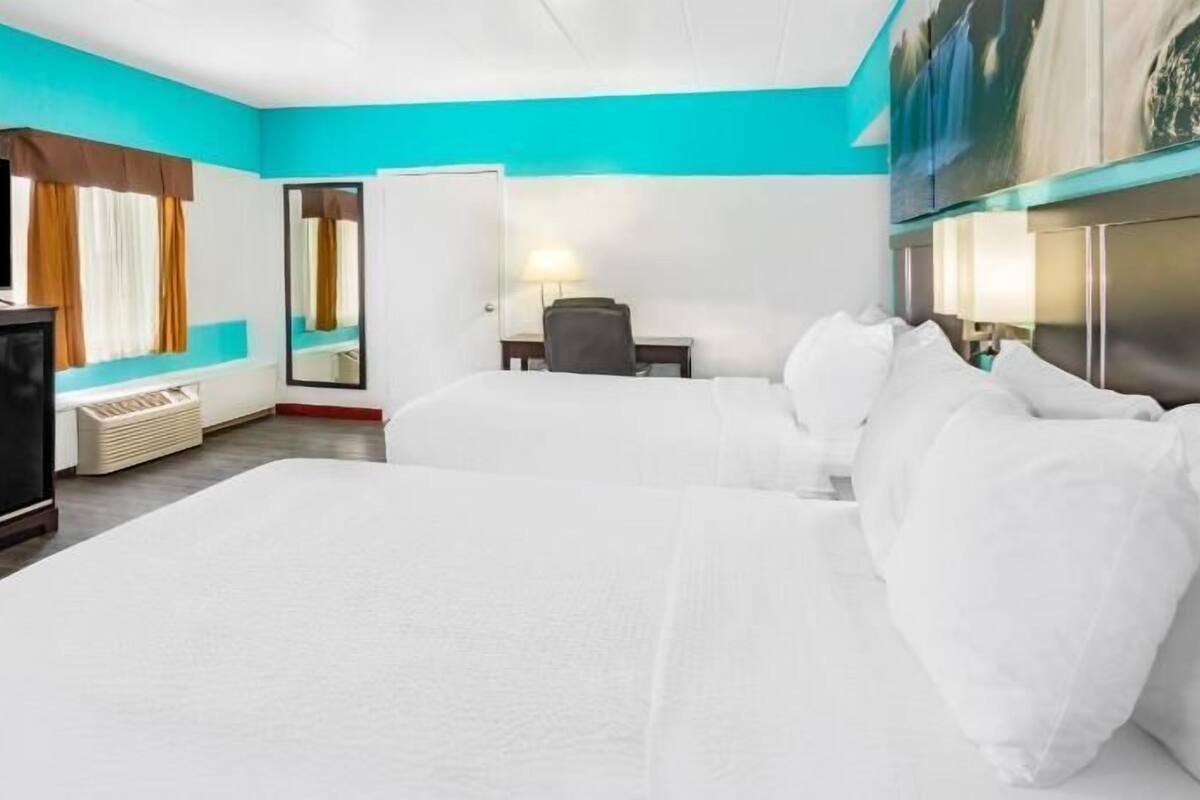 A hotel room with a large bed, a TV, a desk, and a chair.