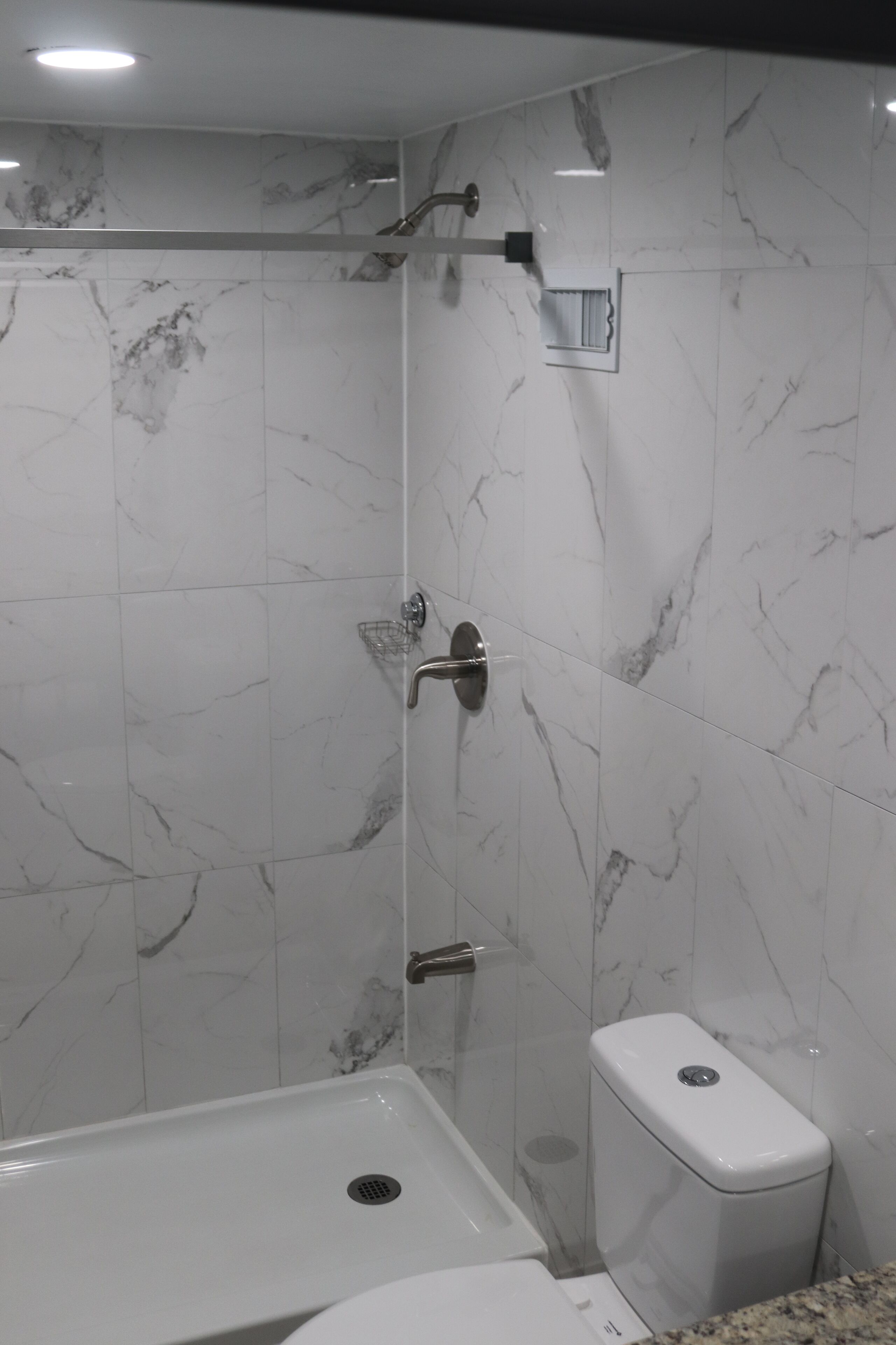 A bathroom with a shower, toilet, and sink.