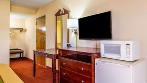 A hotel room with a wooden dresser, a microwave, a television, a bench, and a door. - Econo Lodge Rocky Top (Rocky Top)