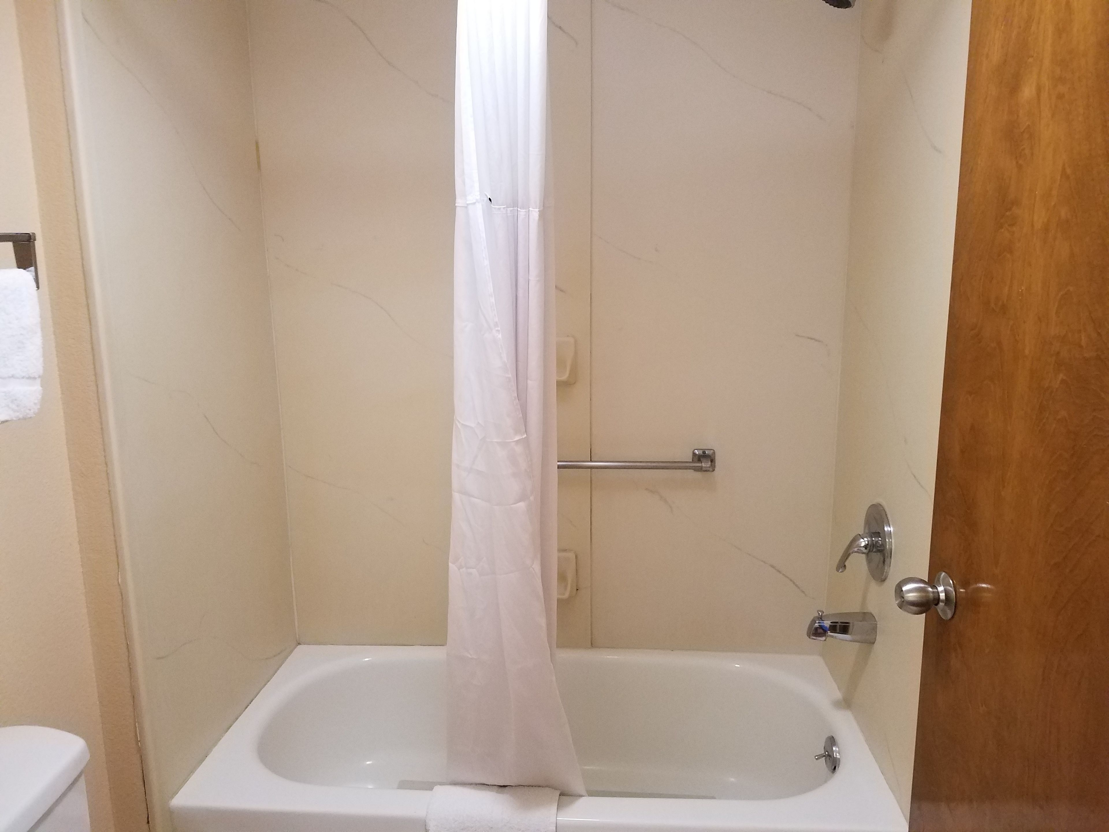 A bathroom with a bathtub, a shower curtain, and a towel rack.