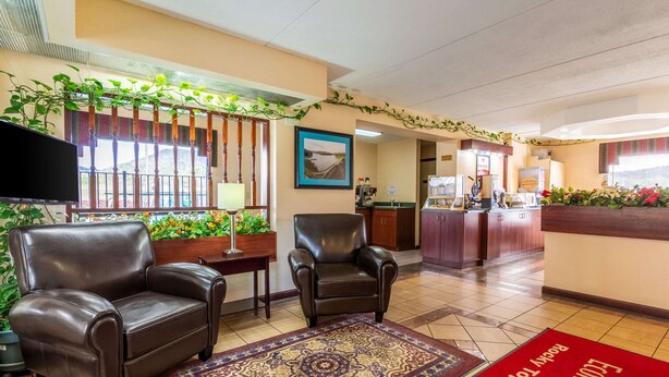 A hotel lobby with leather armchairs, a reception desk, a television, and a view of the outside. - Econo Lodge Rocky Top (Rocky Top)