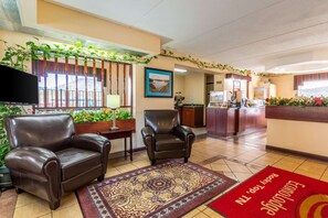 Welcome to our lobby, featuring a reception desk, comfortable armchairs, and a mounted TV.