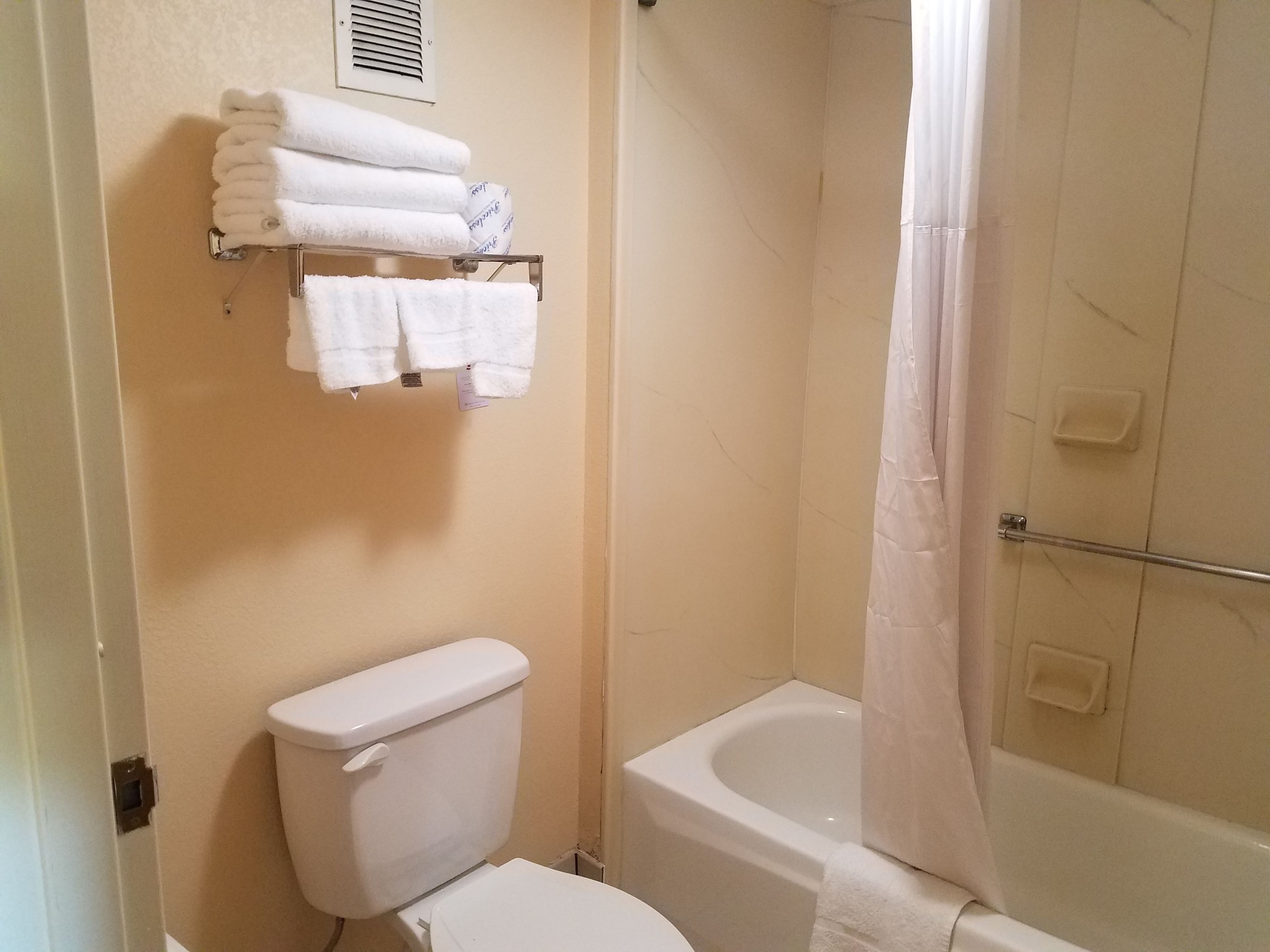 A bathroom with a toilet, a bathtub, and a towel rack with folded towels.