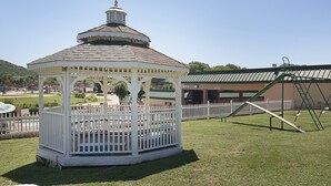 A gazebo with a white fence and a green playground in the background. - Econo Lodge Rocky Top (Rocky Top)