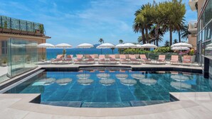 A poolside area with lounge chairs and umbrellas, overlooking the sea. - Canopy by Hilton Cannes (Cannes)
