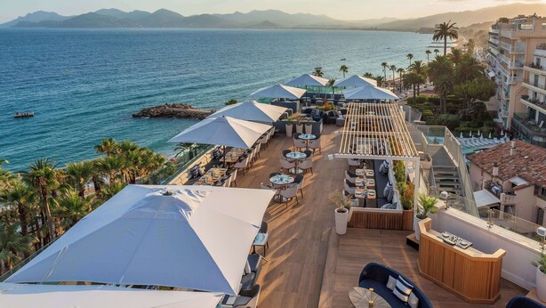 A rooftop terrace with outdoor seating, a reception desk, and a view of the sea and mountains. - Canopy by Hilton Cannes (Cannes)