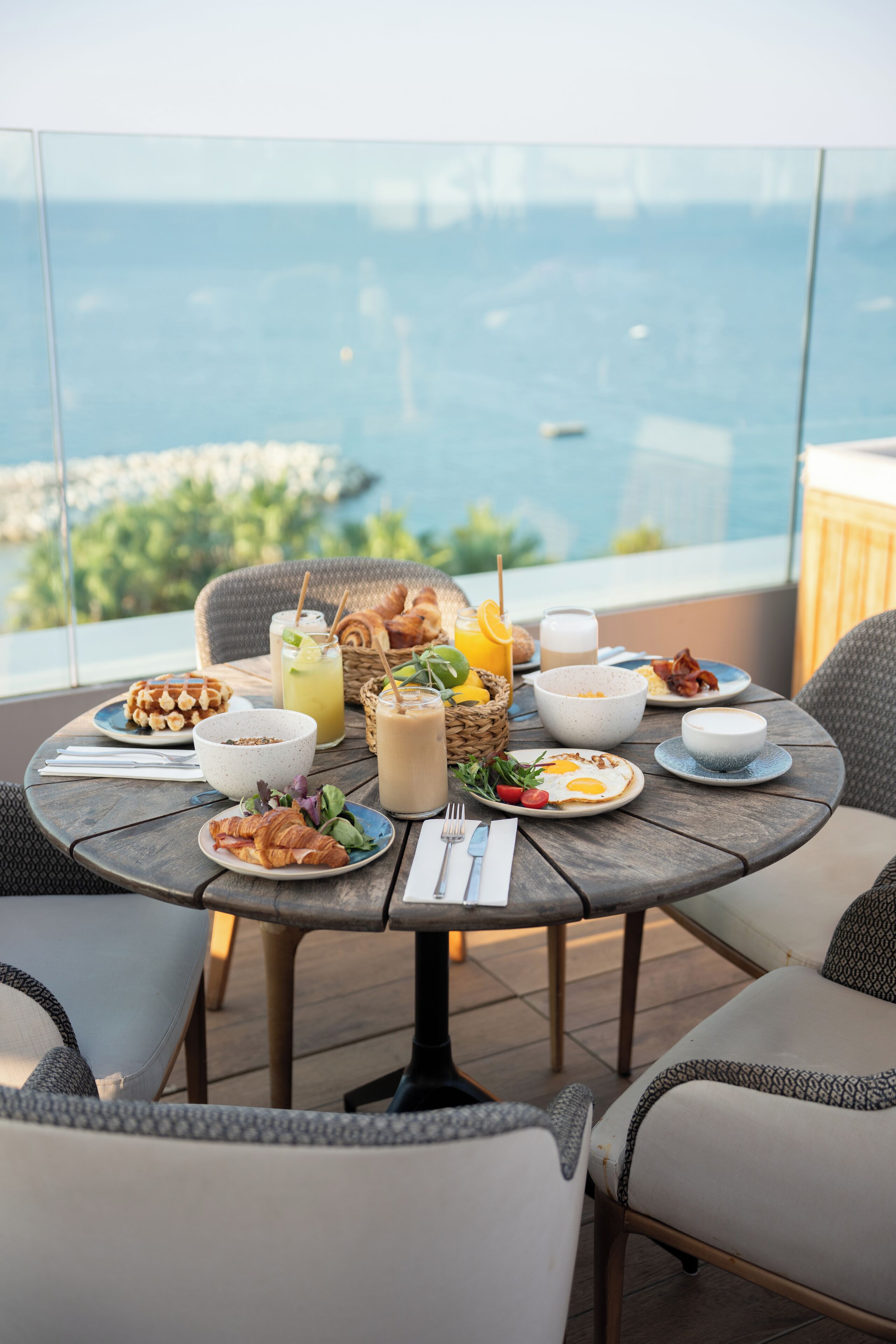 Une table à manger dressée pour le petit-déjeuner, avec vue sur la mer.