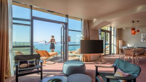 A modern hotel room with large windows, a balcony with a view of the sea, a flat-screen TV, and a dining area. - Canopy by Hilton Cannes (Cannes)