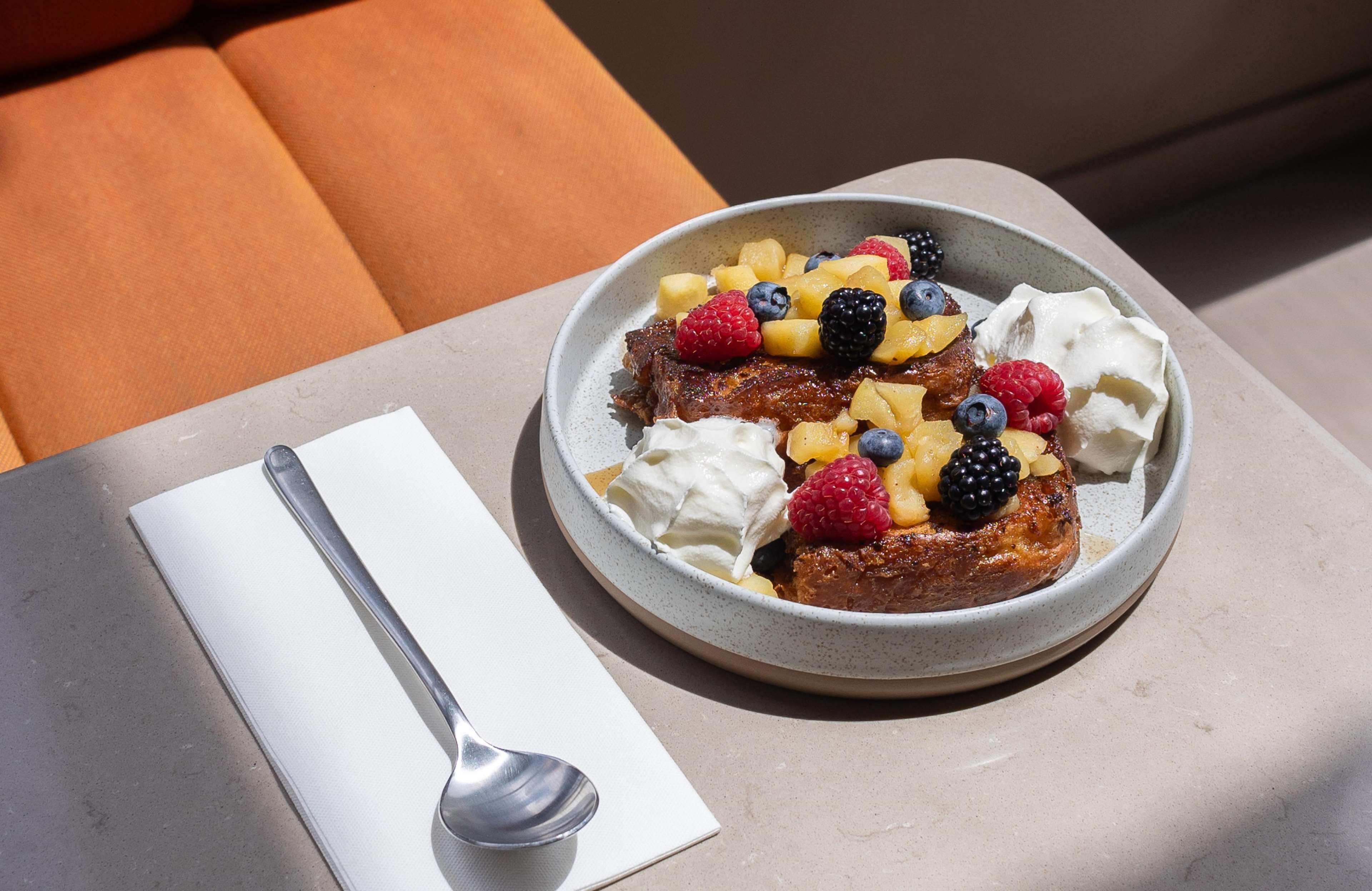 A plate of food with fruits and whipped cream on a table.
