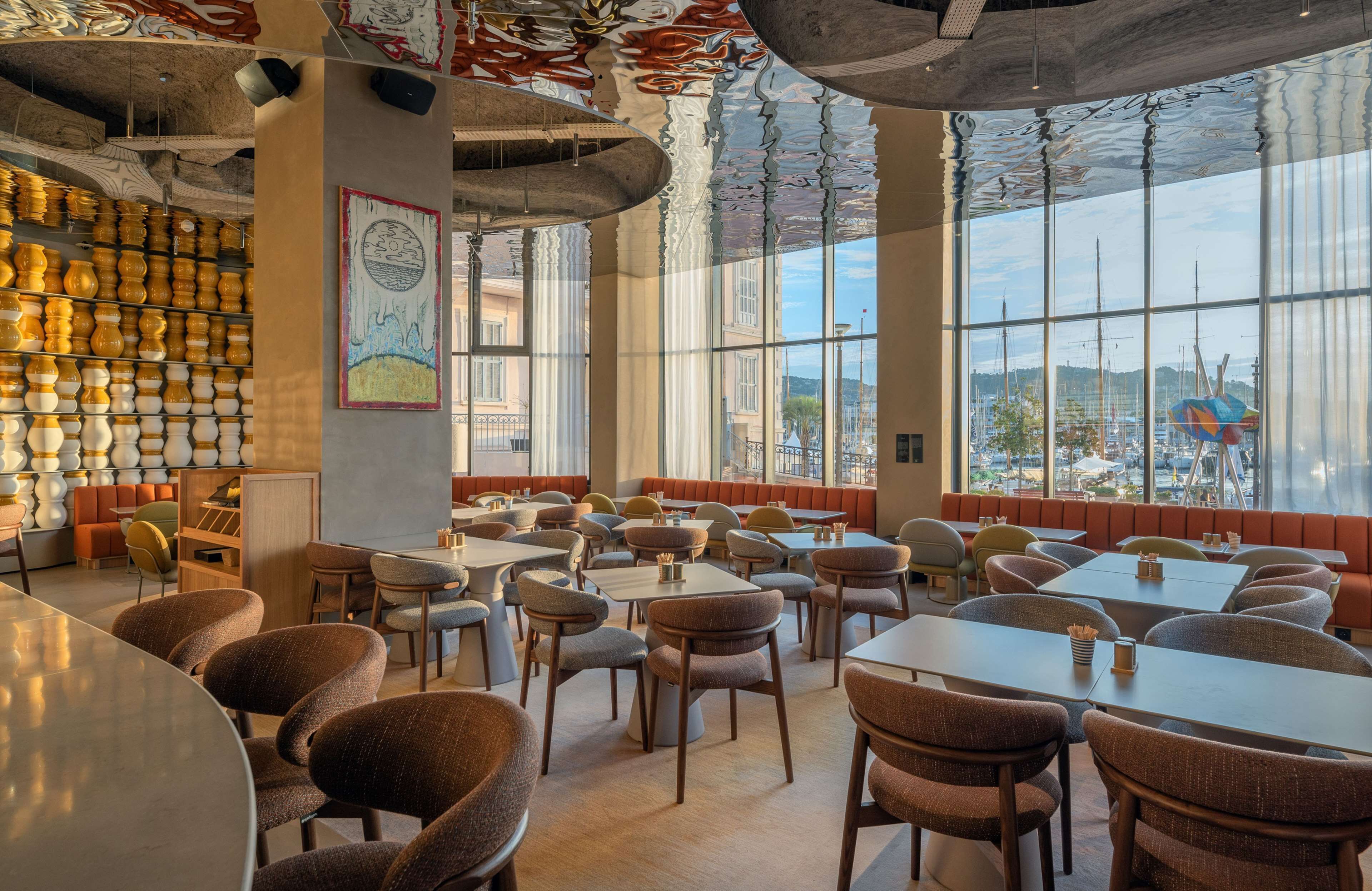 A restaurant with high ceilings, large windows, and a variety of seating arrangements including booths and tables.