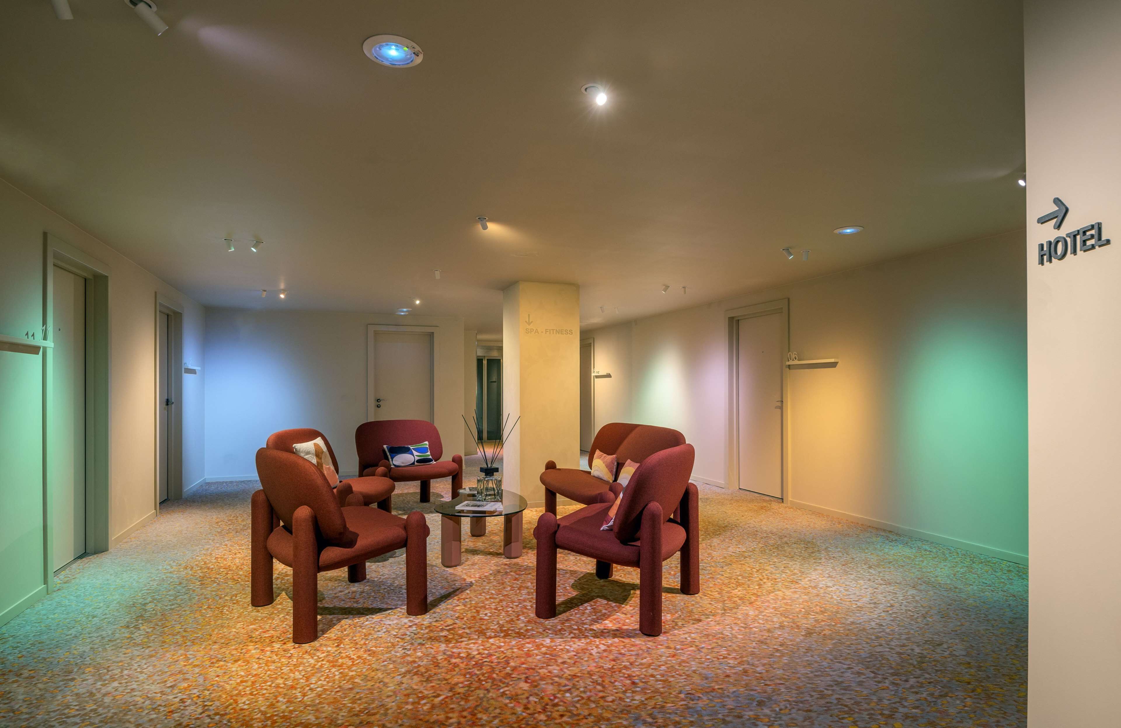 Vestíbulo de hotel con piso alfombrado, una recepción y un letrero que indica la dirección al hotel.