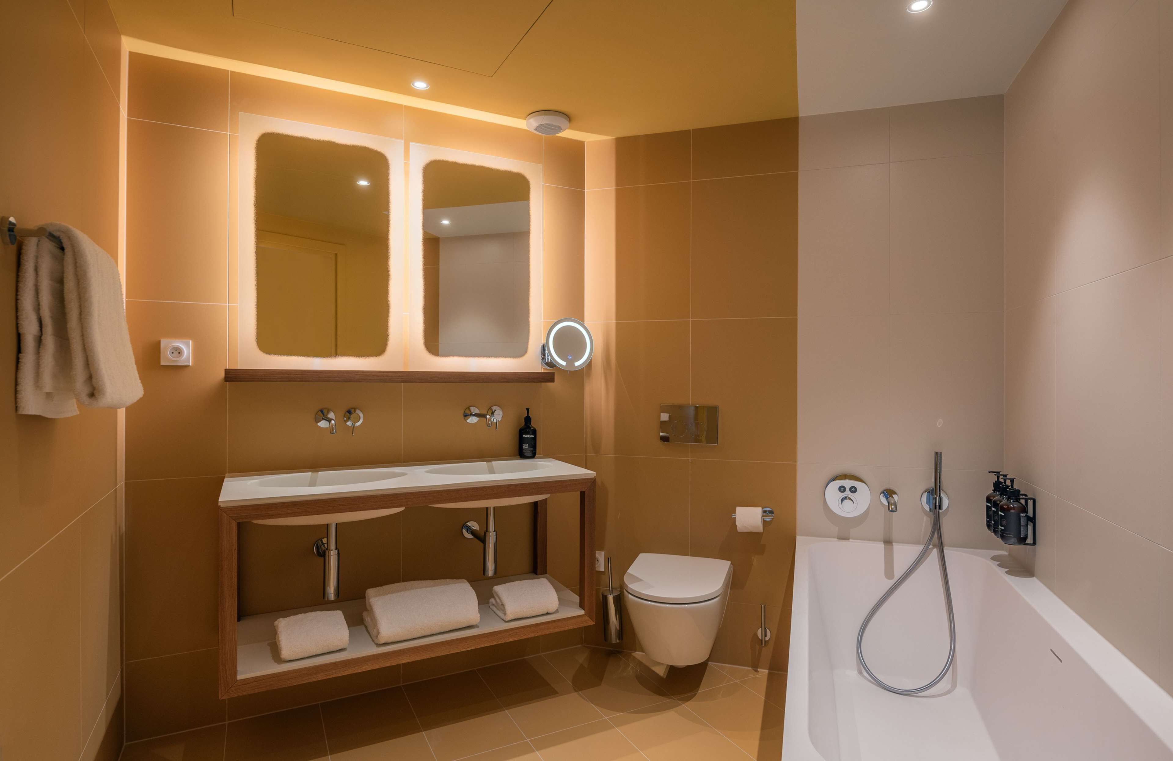 A modern bathroom with a vanity, sink, mirror, toilet, and bathtub.