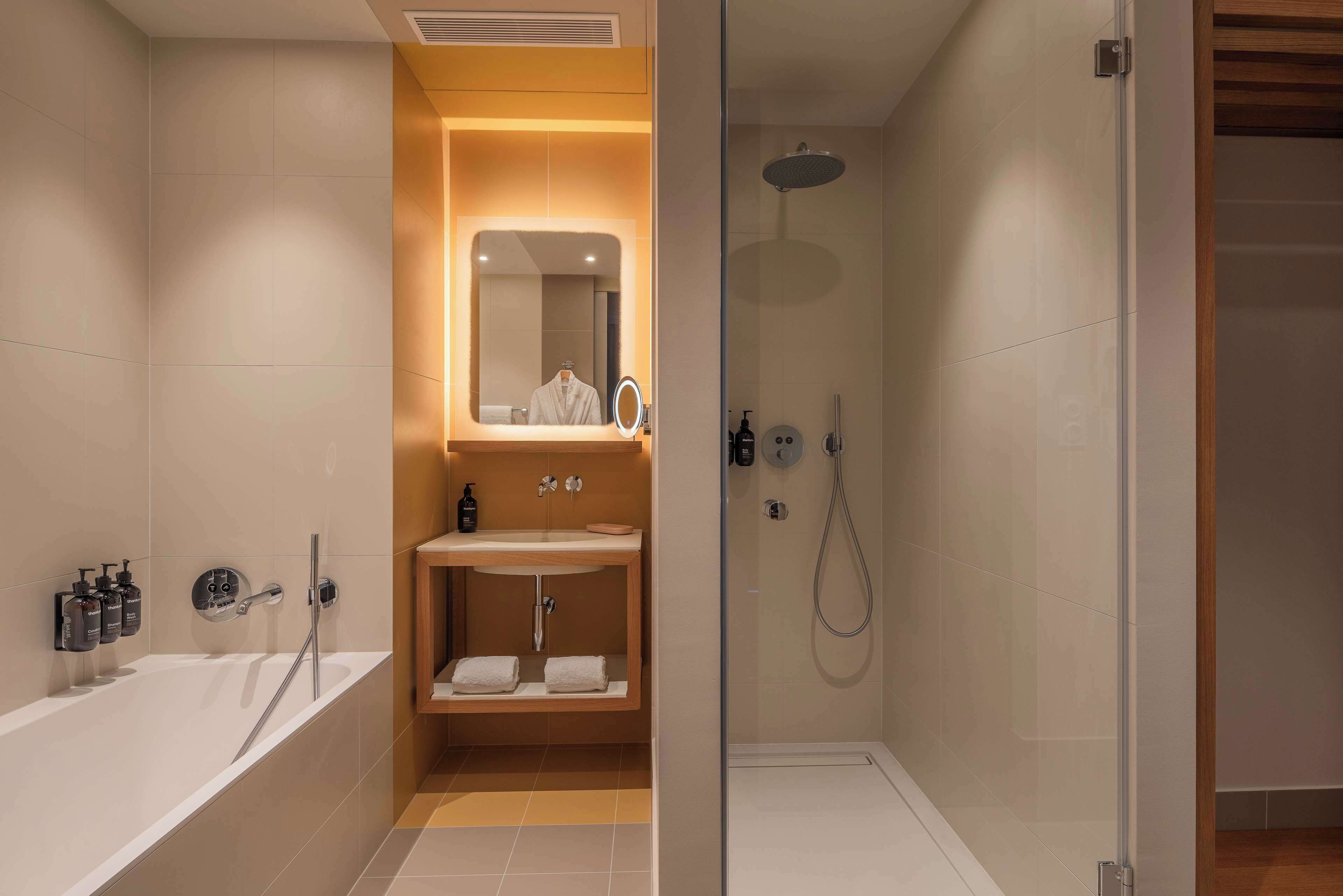 Une salle de bain moderne équipée d’une baignoire, d’une douche à parois de verre, d’un meuble-lavabo avec miroir et d’un porte-serviettes.