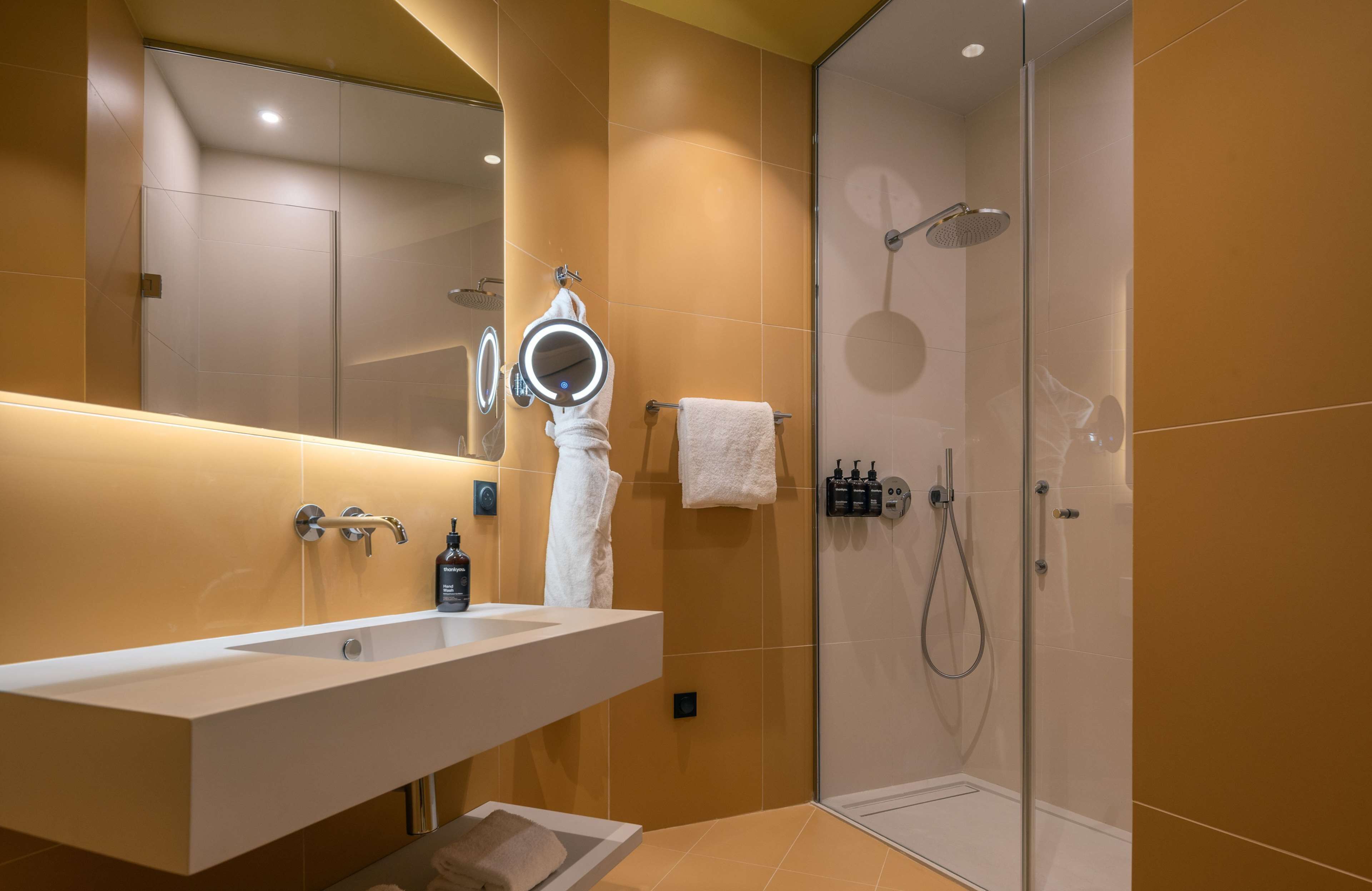 A modern bathroom with a large mirror, a sink, and a shower area.